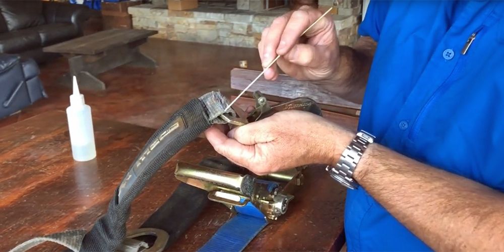 man in blue shirt pointing to a worn portion of a tie-down strap