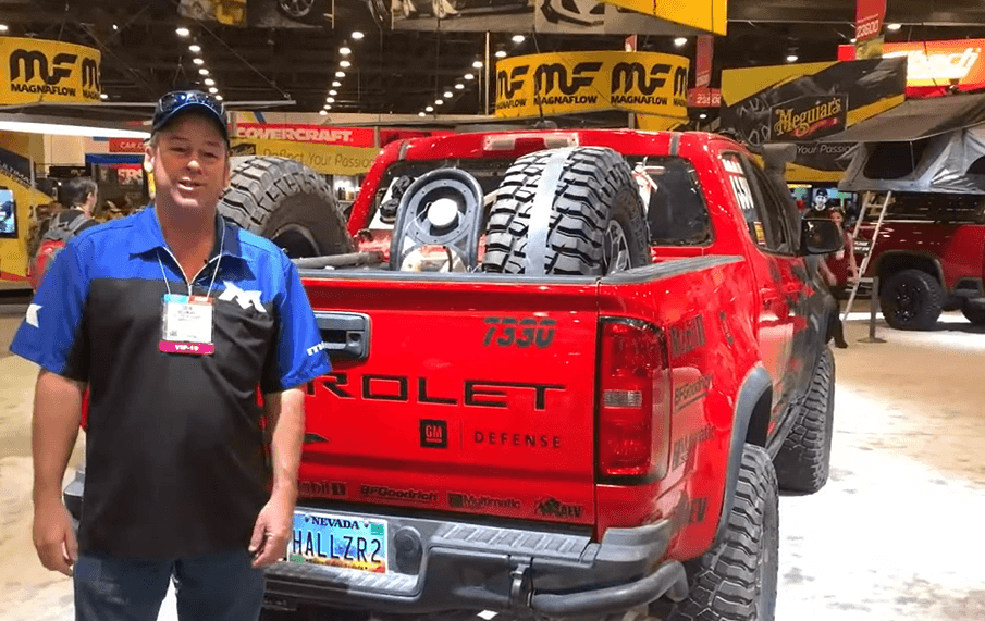 Colin McLemore at SEMA in 2019 standing in front of Hall Racing pickup with Mac's over-the-tire straps