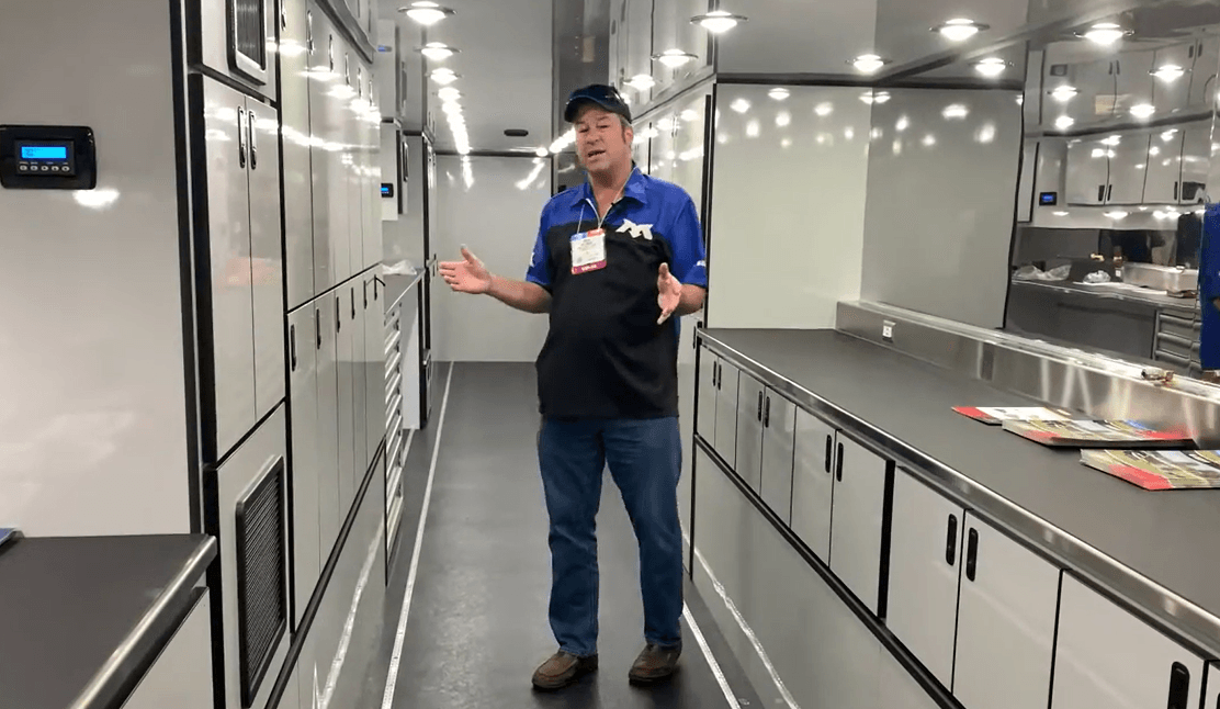 Colin McLemore at SEMA in 2019 standing in a Featherlite trailer with VersaTie L-track