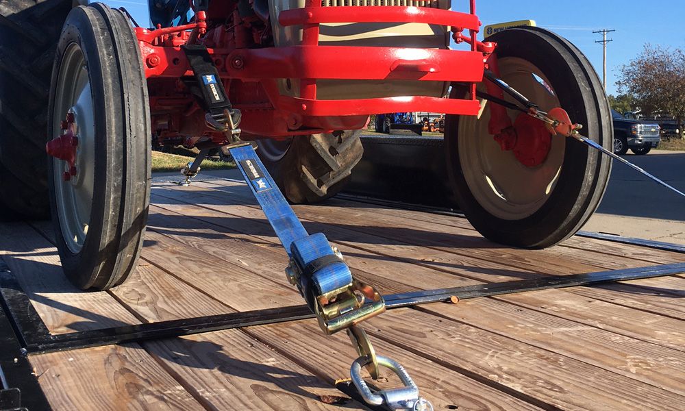 Mac's Ultra Pack tie-down straps securing an antique tractor to an open deck trailer