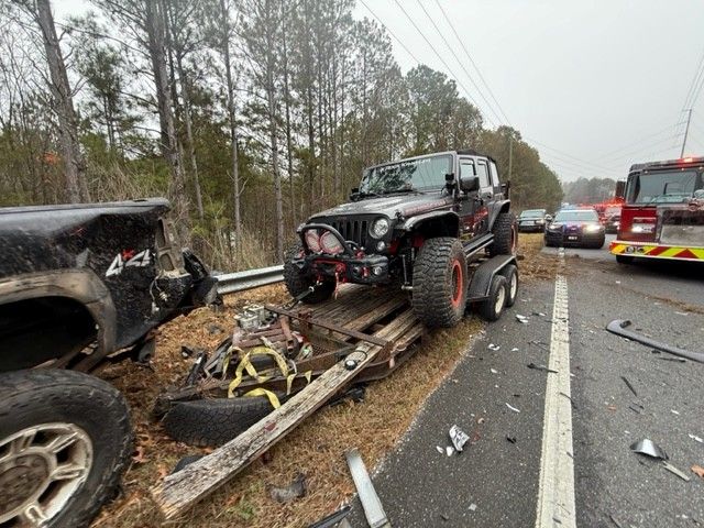 Trailer sheared off truck with Jeep secured and emergency response vehicles